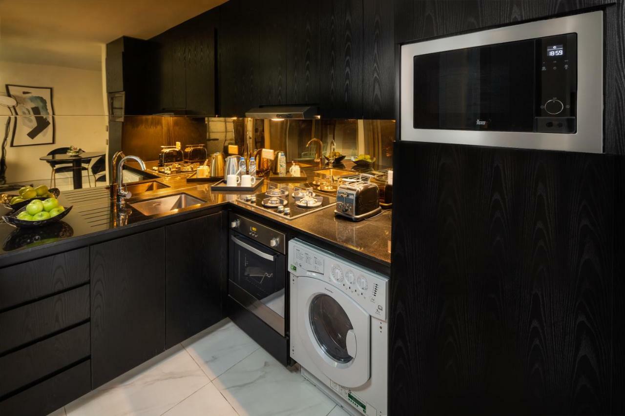 두바이 밀레니엄 아트리아 비즈니스 베이 아파트 호텔 외부 사진 The photo shows a modern kitchen with a sleek design. The cabinets and surfaces are predominantly black, creating a contemporary look. There is a stainless steel microwave mounted above the countertop, and on the counter, various kitchen appliances l